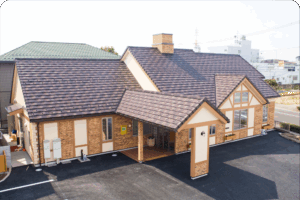 木造建築の介護施設外観。瓦葺き屋根と木製の柱が特徴的な建物全景。